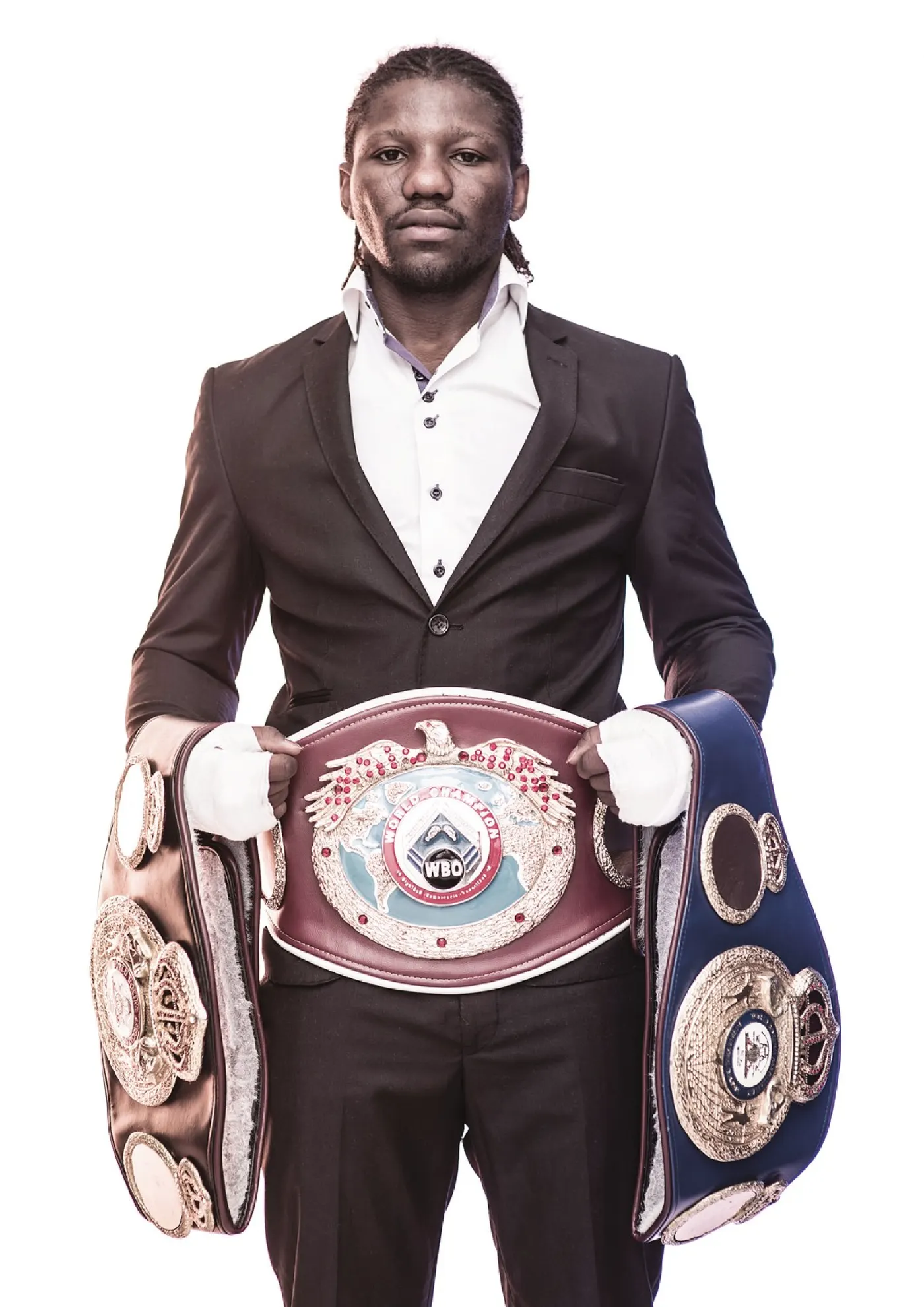 Hassan N'Dam en costume, portant ses ceintures de champion du monde